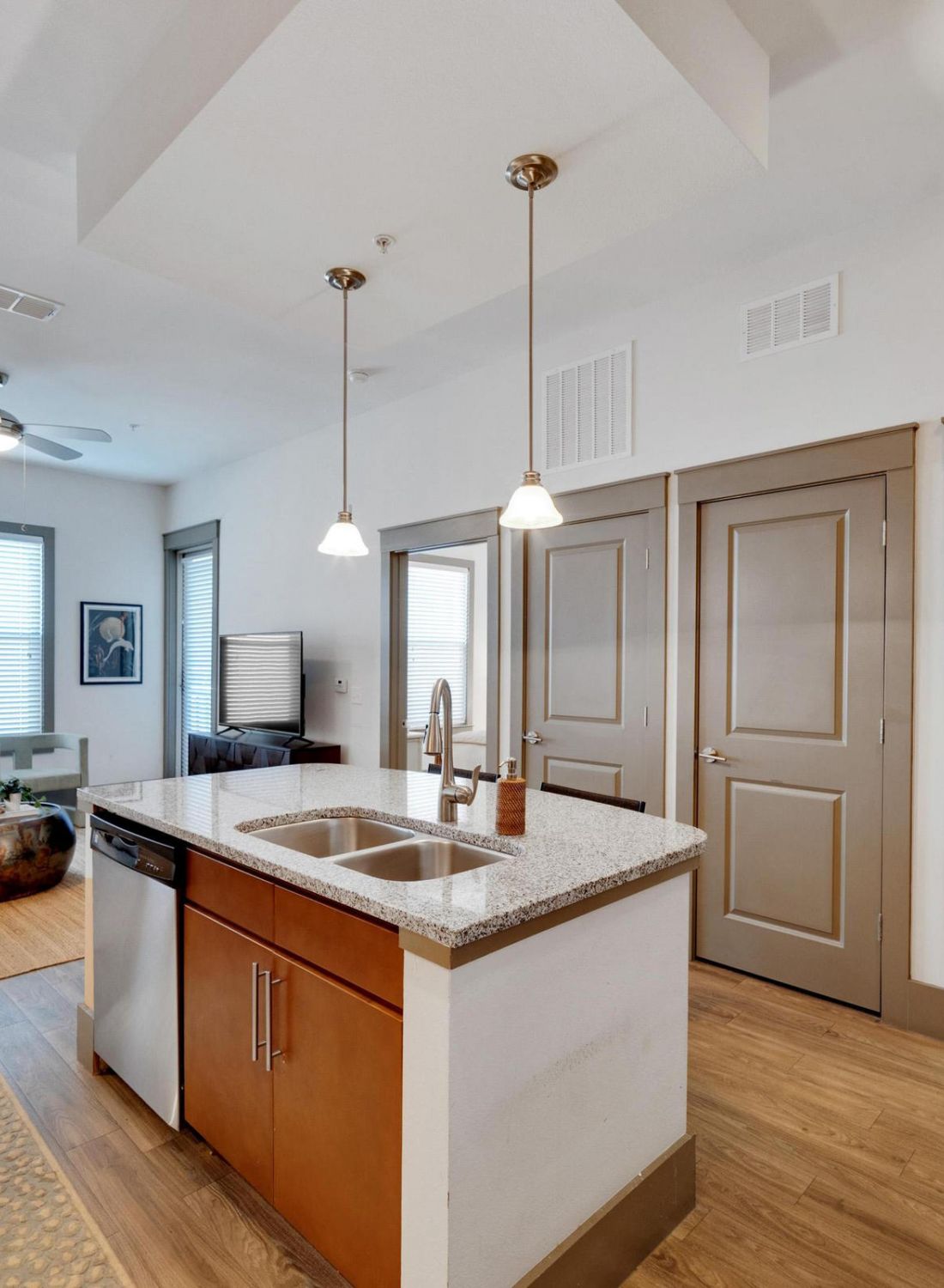 Modern apartment with kitchen island, living area, dining table, and view into bathroom with bathtub.